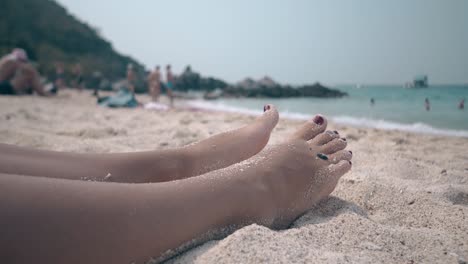 relaxed-girl-with-red-pedicure-sleeps-on-sand-coastline