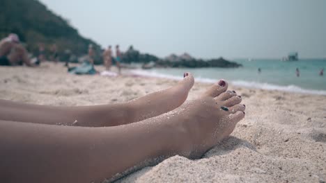 relaxed girl with red pedicure sleeps on sand coastline