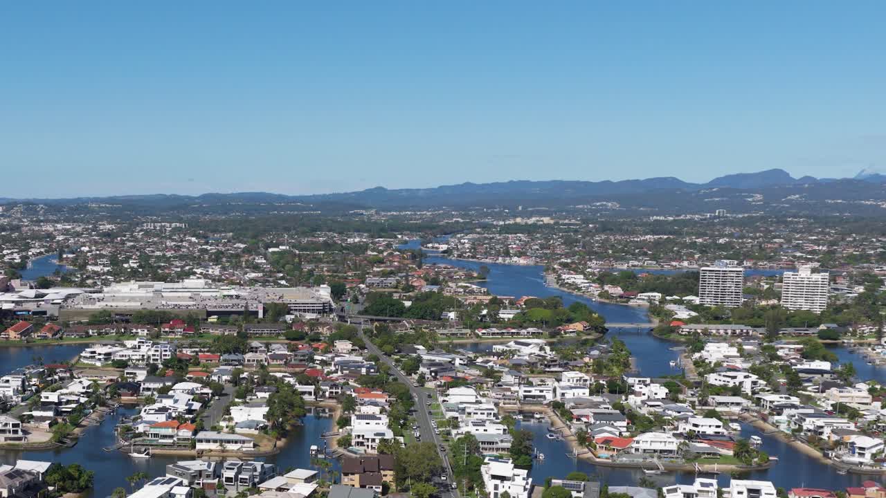 Aerial footage showcasing a sprawling urban area with rivers, buildings, and distant mountains under clear blue skies