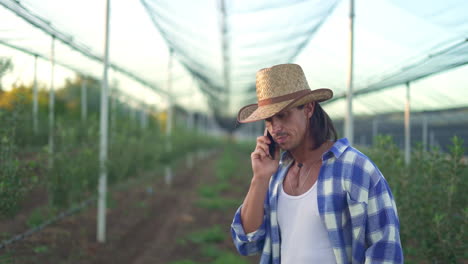 farmer talking on phone in orchard