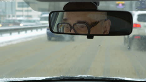 senior man driving a car in winter