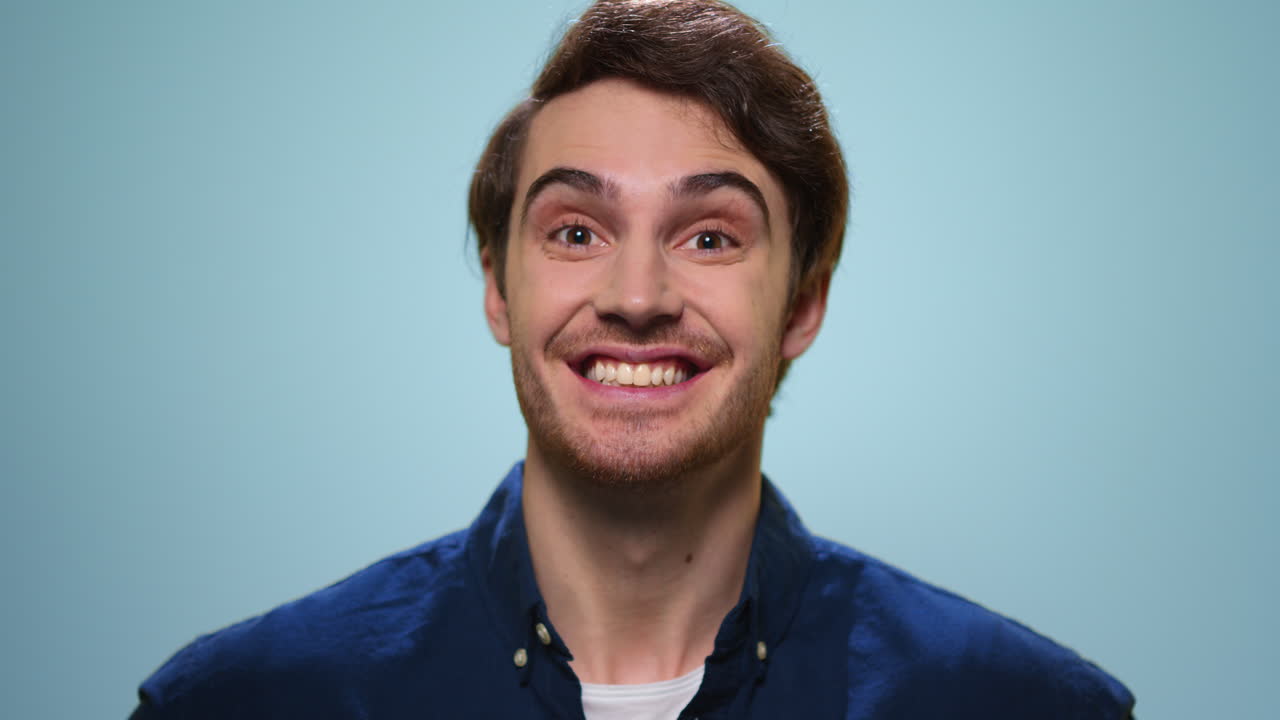 Surprised man posing on blue background. Excited guy looking at camera
