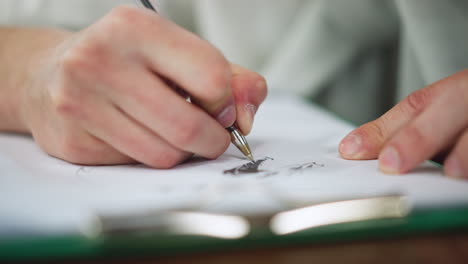 close shot showing artist holding ink brush in mouth to point at ongoing painting while hands hover over wet strokes under soft studio light capturing creative process focus and fine detail