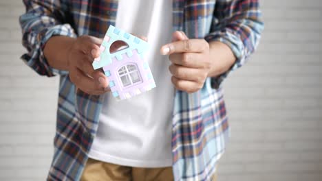 persona que sostiene una casa de juguetes en miniatura