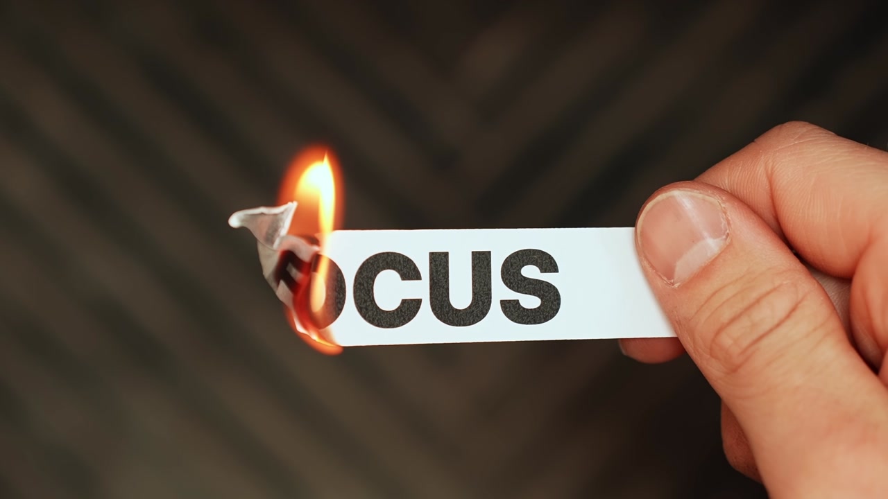 Burning “focus” label symbolizes distraction, procrastination, scattered thinking, and loss of concentration in a bold conceptual close-up.