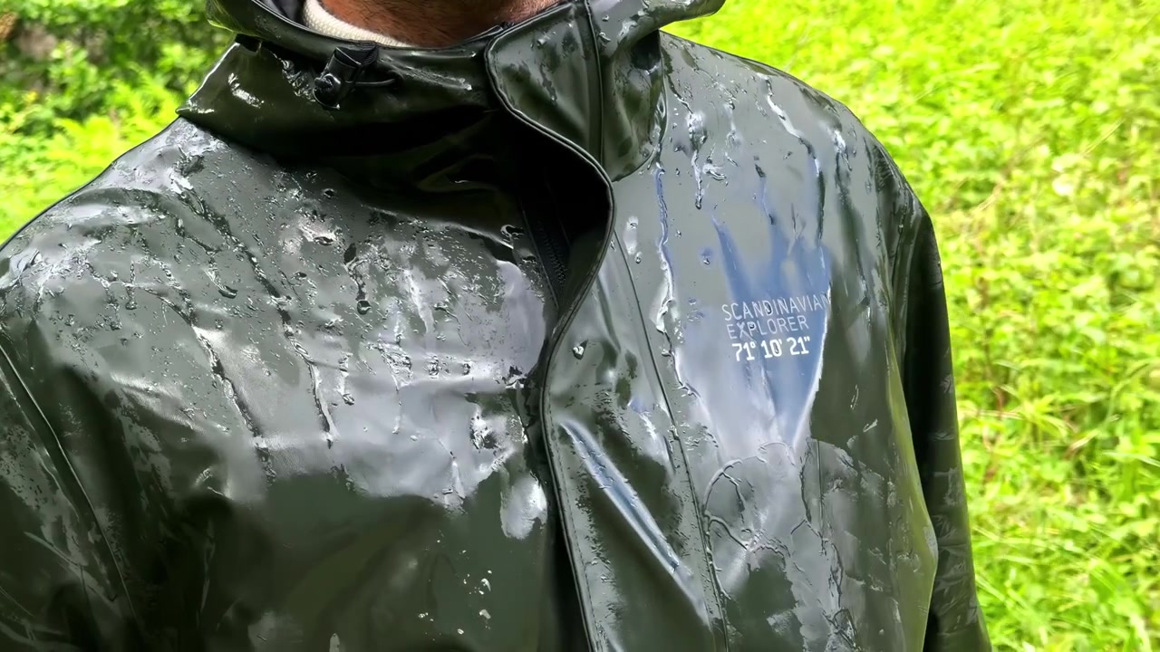 Personne en veste de pluie en extérieur avec des gouttelettes d'eau, avec un paysage norvégien verdoyant et luxuriant en arrière-plan