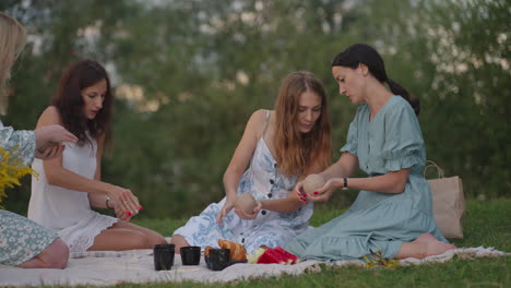 A-group-of-young-women-sculpt-from-clay-listen-to-the-master-communicate-in-the-open-air.-The-master-explains-the-correct-technique-of-modeling.-Creative-activity-hobbies-master-class-training