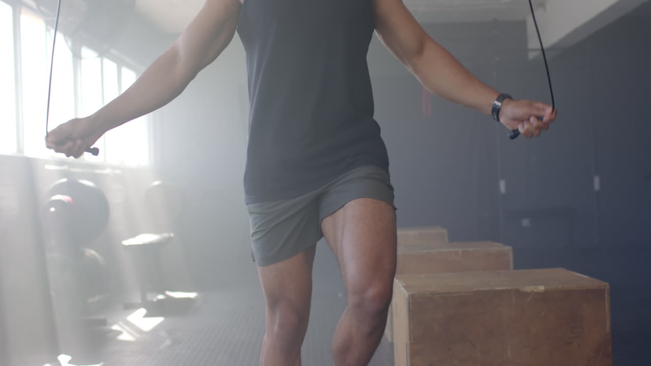 Jumping rope, man exercising in gym wearing tank top and shorts