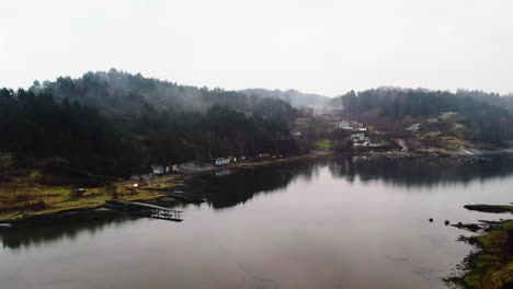 Un-Día-Sereno:-Casas-Nórdicas-Costeras-En-Medio-De-La-Niebla-Del-Lago-Y-El-Bosque,-Vista-Aérea