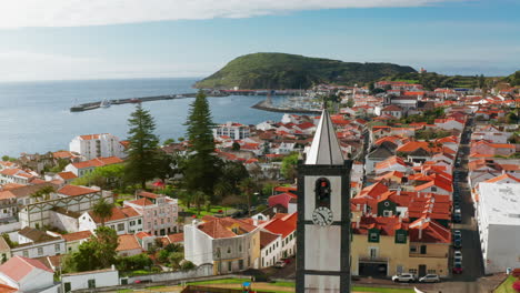 Filmische-Drohnenaufnahme-Aus-Der-Luft-Der-Malerischen-Stadt-Horta-Auf-Der-Insel-Faial,-Azoren-–-Portugal.-Hohe-Sicht-Auf-Die-Am-Hafen-Angedockten-Schiffe,-Grüne-Landschaft-Im-Hintergrund