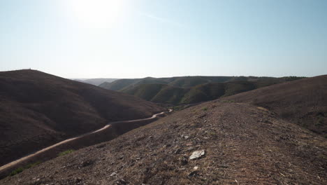 dirt trails and barren hills in the harsh landscape of algarve portugal - tilt up reveal shot