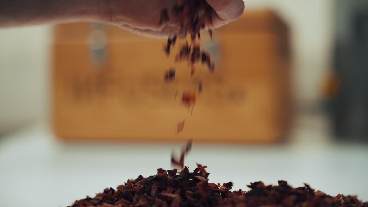 향기로운 건조한 향신료 허브가 테이블 위에 떨어지는 남성 손의 클로즈업  ⁇