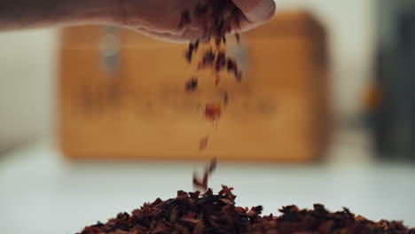 close up shot of a male hand letting aromatic dried spice herbs fall on the table