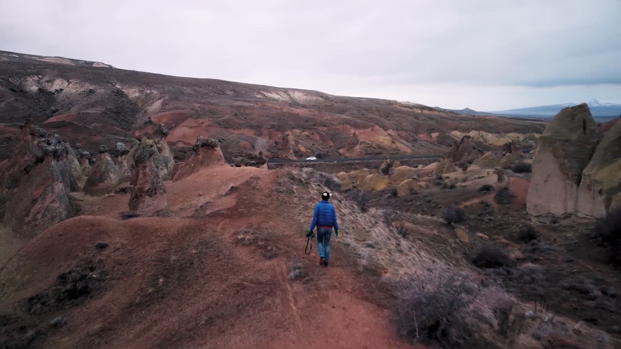 una turista caucásica disfruta de la libertad y viaja de vacaciones al aire libre caminando entre chimeneas de hadas en el valle de devrent, capadocia
