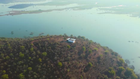 aerial drone shot of a hill top temple with reservoir in background in gwalior , india