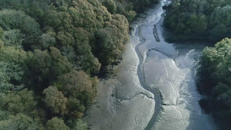 Aerial-view-over-a-shallow,-muddy-river-mouth-in-Cornwall,-UK