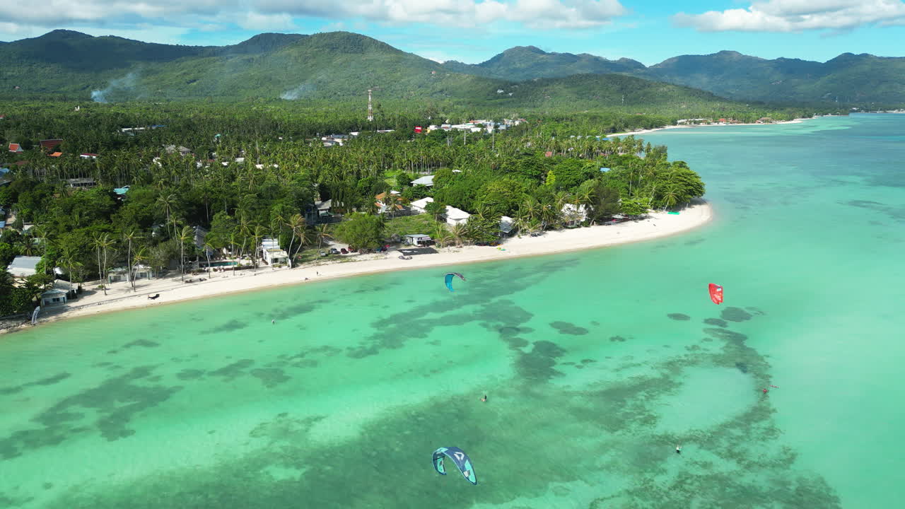 People Kitesurfing in Koh PhanGan tropical lagoon in sunny day