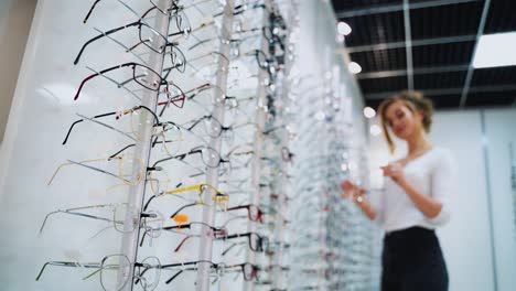 close-up glasses on the stand on the blur background with customer. fashionable eyeglasses in the optical store. vision concept.