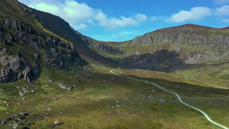 aerial view of a mountain valley and winding path leading to a waterfall in the south of ireland during summer