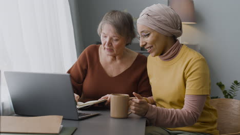 arabic woman teaching an elderly woman to use a laptop at home 3