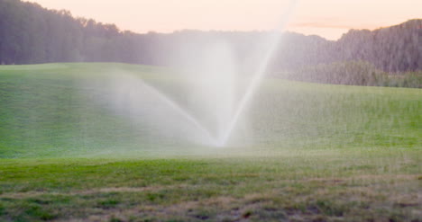 Mittlerer-Schuss-Grassprinkler-Spritzt-Wasser-über-Den-Rasen