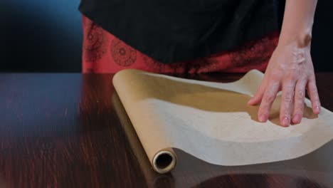 cook cutting a section of baking paper with scissors