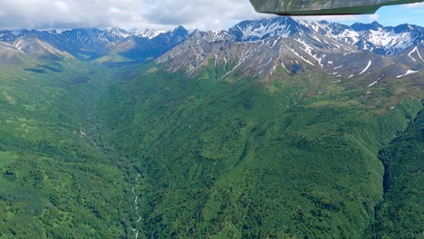 volando a lo largo de un valle montañoso remoto en la cordillera talkeetna de alaska, filmado desde un pequeño avión con una cámara de acción