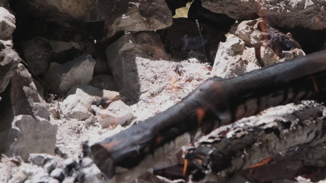 불타는 불꽃과 작은 불꽃이 재와 불타는 나무를 가로질러 보이는 불꽃