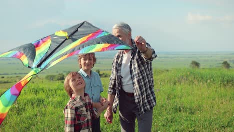 close-up view of a caucasian senior man with his grandchildren in the park while they are flying a kite on a sunny day