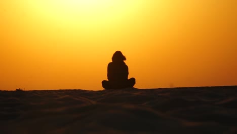 girl sitting at lotos position at the sunrise beach