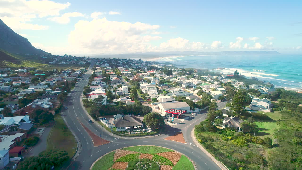 Aerial riser from roundabout reveals affluent Voëlklip seaside neighborhood
