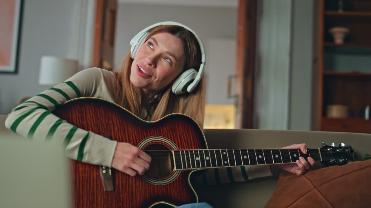 Girl studying guitar play in headphones looking laptop online lesson close up.