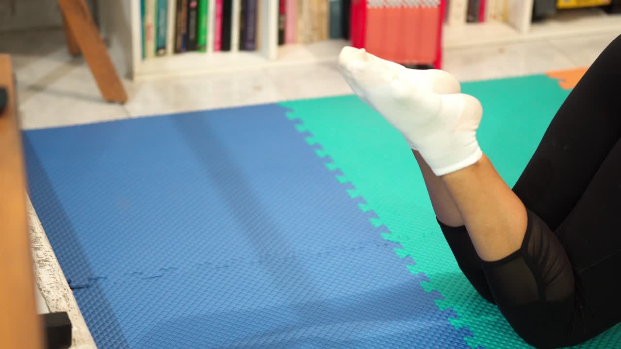 Soft sock-clad foot stretched upward, doing an exercise on a mat indoors