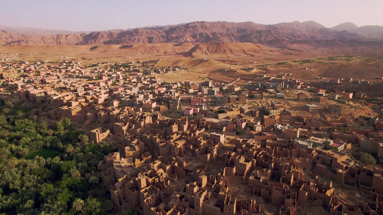 Tinghir, Drâa Tafilalet, Marocco, con architettura storica di ksar, fitti palmeti ed espansione urbana desertica sotto i sistemi montuosi dell'Alto Atlante e dell'Anti Atlante, rivelazione con sorvolo in avanti del drone