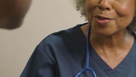 Close-Up-Smiling-Middle-Aged-Doctor-Talking-to-Patient