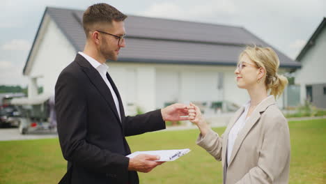 real estate agent hands keys to new property buyer