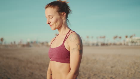 sporty tattooed girl stretching before workout by the sea.