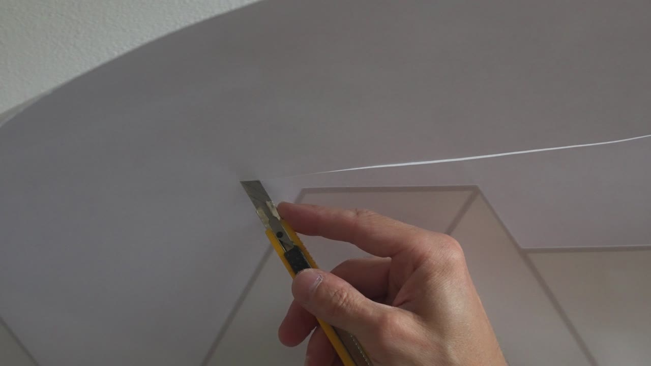 aplicador de vinilo profesional que recorta el exceso de material durante la instalación del diseño con una hoja de bisturí afilada