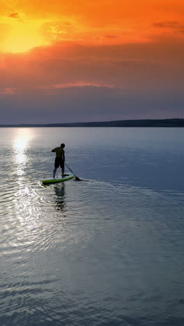 man sailing on river. sports training on water against beautiful sunset. athlete is rowing on the evening water while standing with an oar. water sports. vertical video