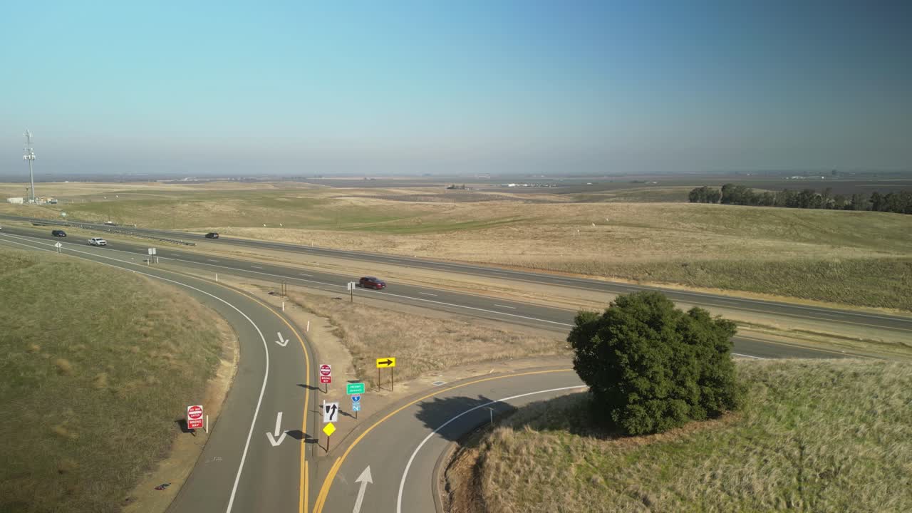 A static drone view of Highway 5 near Newman, featuring orderly farmland rows, gently curving roads, and serene rural vistas.