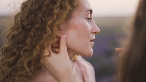 young woman put on earrings to her girlfriend, outdoors