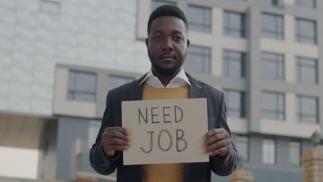 man holding 'need job' sign