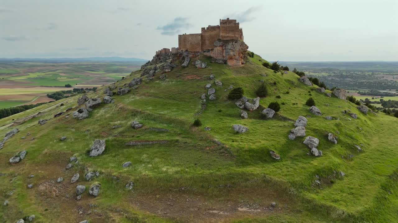 An aerial drone pull-back shot of the caliphate vast and imposing fortress of Gormáz, in Soria, Spain. Shot taken at the golden minute.