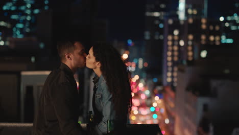 young caucasian couple kissing on rooftop at night enjoying romantic relationship in peaceful urban city evening