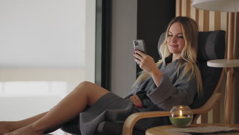 calm weekend in spa-center young blonde lady is using smartphone and relaxing in lounge room