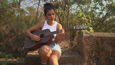 beautiful young girl playing guitar outdoors.