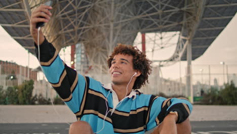 blogger positivo haciendo selfie bajo el puente de primer plano. teléfono inteligente de mensajería adolescente