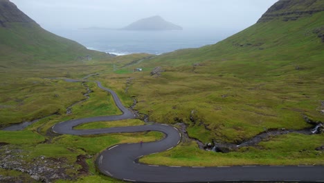 woman stopped on winding road nordadalsskard in faroe islands