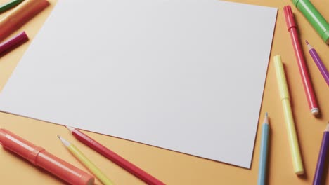 Close-up-of-blank-sheet-of-paper-with-school-stationery-on-beige-background,-in-slow-motion