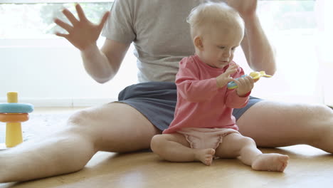 padre irreconocible jugando con el bebé exitado y sentado